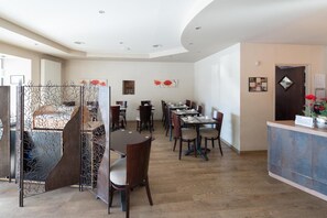 Un amplio comedor con varias mesas y sillas, una recepción y un diseño de techo moderno.