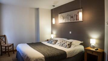 A neatly made bed with a dark headboard, two bedside lamps, and a wall-mounted artwork.