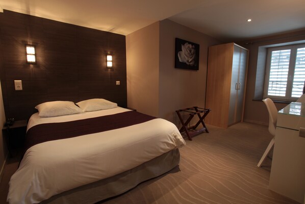 Un dormitorio con cama, escritorio y silla.