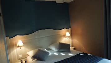 A hotel room with a bed, two bedside lamps, and a nightstand with a remote control.