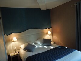A hotel room with a bed, two bedside lamps, and a nightstand with a remote control.