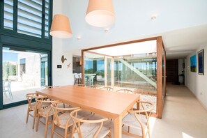 Une salle à manger moderne avec une table et des chaises en bois, de grandes fenêtres et une cloison en verre.