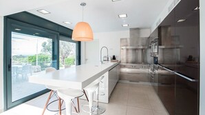 A modern kitchen with a large island, stainless steel appliances, and a pendant light.