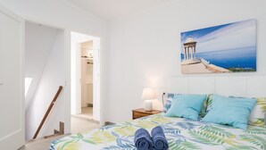 A bedroom with a bed, pillows, a nightstand, a lamp, a painting, and a staircase. - Charming town house with pool - Casa Can Tatau (Santañyí)