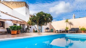 A swimming pool with lounge chairs, potted plants, and a tree with orange fruits. - Charming town house with pool - Casa Can Tatau (Santañyí)
