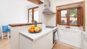 A kitchen with a white countertop, a fruit bowl, a built-in oven, and wooden cabinets. - Charming town house with pool - Casa Can Tatau (Santañyí)
