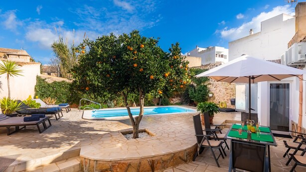 A pool area with stone flooring, a tree with orange fruits, and outdoor seating. - Charming town house with pool - Casa Can Tatau (Santañyí)