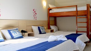 A hotel room with two beds, a bunk bed, a bedside table with a lamp, and an air conditioning unit. - Mandala Hotel (Encarnacion)