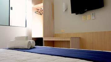Una habitación de hotel con cama, escritorio, televisor y armario.