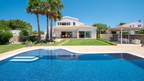 Une maison moderne dotée d’une piscine, d’un patio couvert et d’une pelouse bien entretenue.