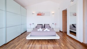 Une chambre moderne avec un lit, des tables de chevet, un miroir et un plancher en bois.