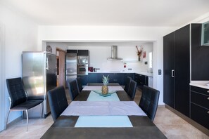 Una cocina moderna con comedor, que incluye una mesa con sillas, un refrigerador, un horno y un microondas.