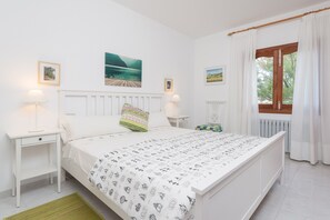 A bedroom with a bed, bedside tables, a window with curtains, and wall art.