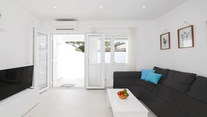 Ein modernes Wohnzimmer mit einem schwarzen Sofa, einem weißen Couchtisch mit Obst und einem großen Fenster mit Blick.