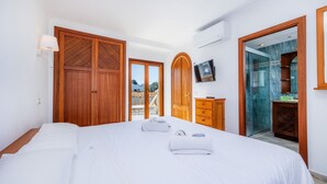 Ein Schlafzimmer mit einem großen Bett, einem Holzschrank und einem an der Wand befestigten Fernseher.