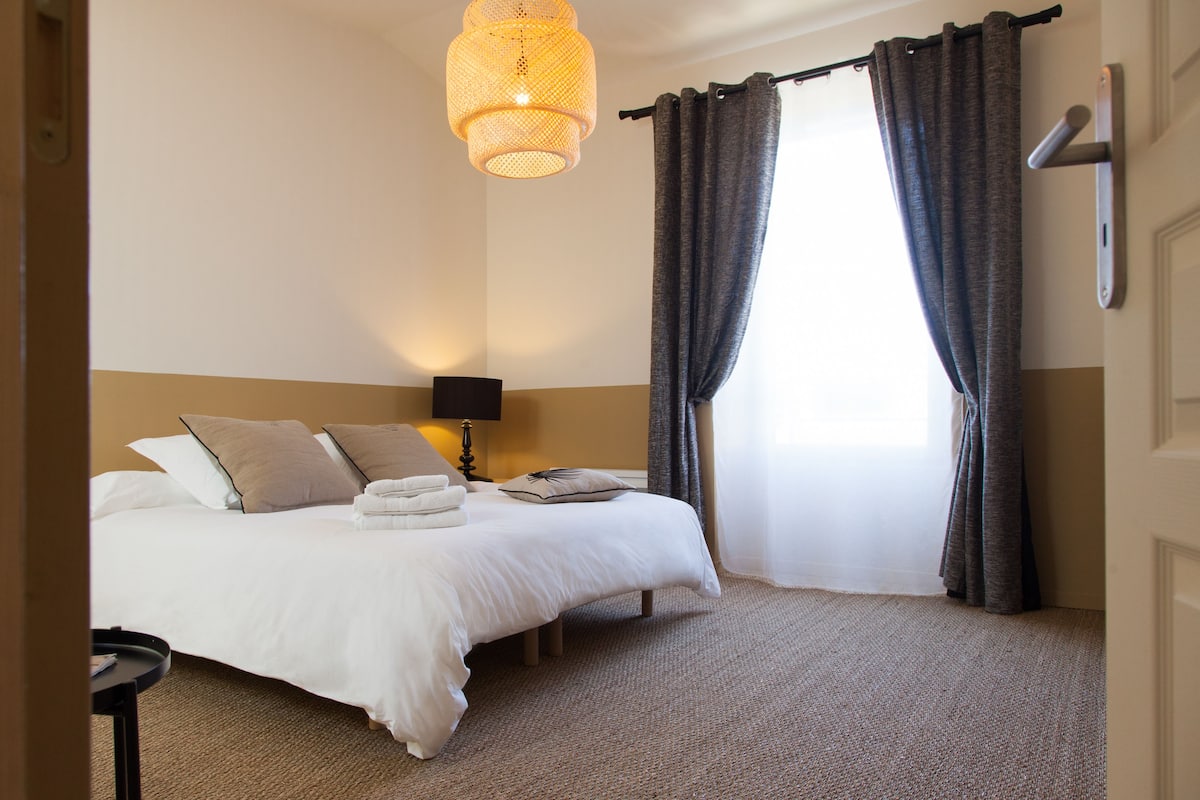 Una camera d'albergo con un letto, una lampada da comodino, una finestra con tende e un pavimento tappezzato.