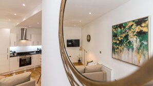 A modern kitchen with white cabinetry, a built-in oven, and a stainless steel range hood. - Hounds Gate Court (Nottingham)