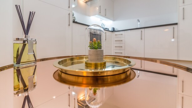 A modern kitchen with white cabinets, a stainless steel sink, and a round glass table with a central decorative item. - Hounds Gate Court (Nottingham)