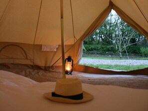 A tent interior with a lantern and a hat on the floor.