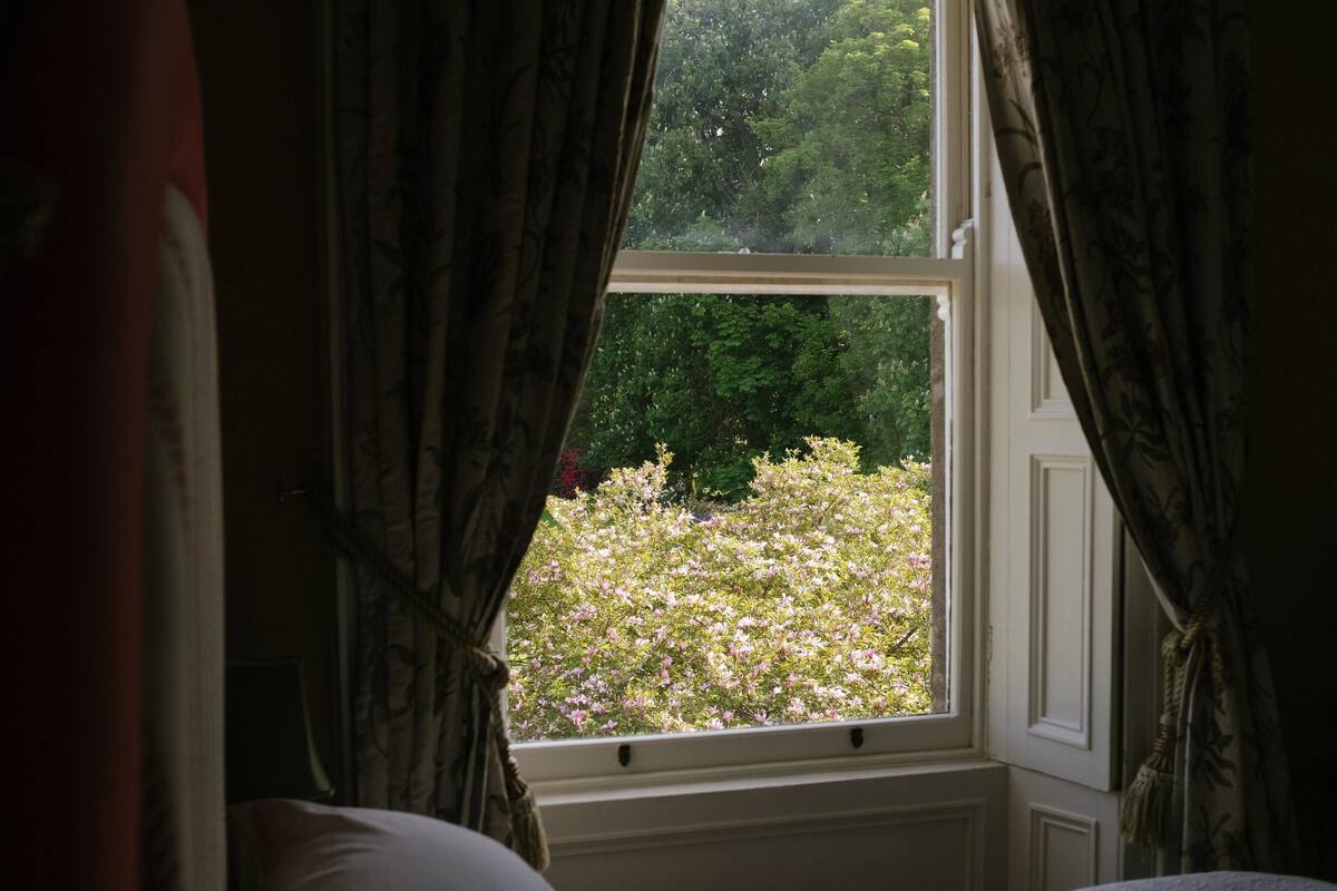 Ein Schlafzimmer mit einem Fenster, das auf einen Garten blickt.