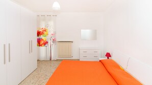 Ein Schlafzimmer mit Bett, Kleiderschrank, Heizkörper und einem Spiegel an der Wand.
