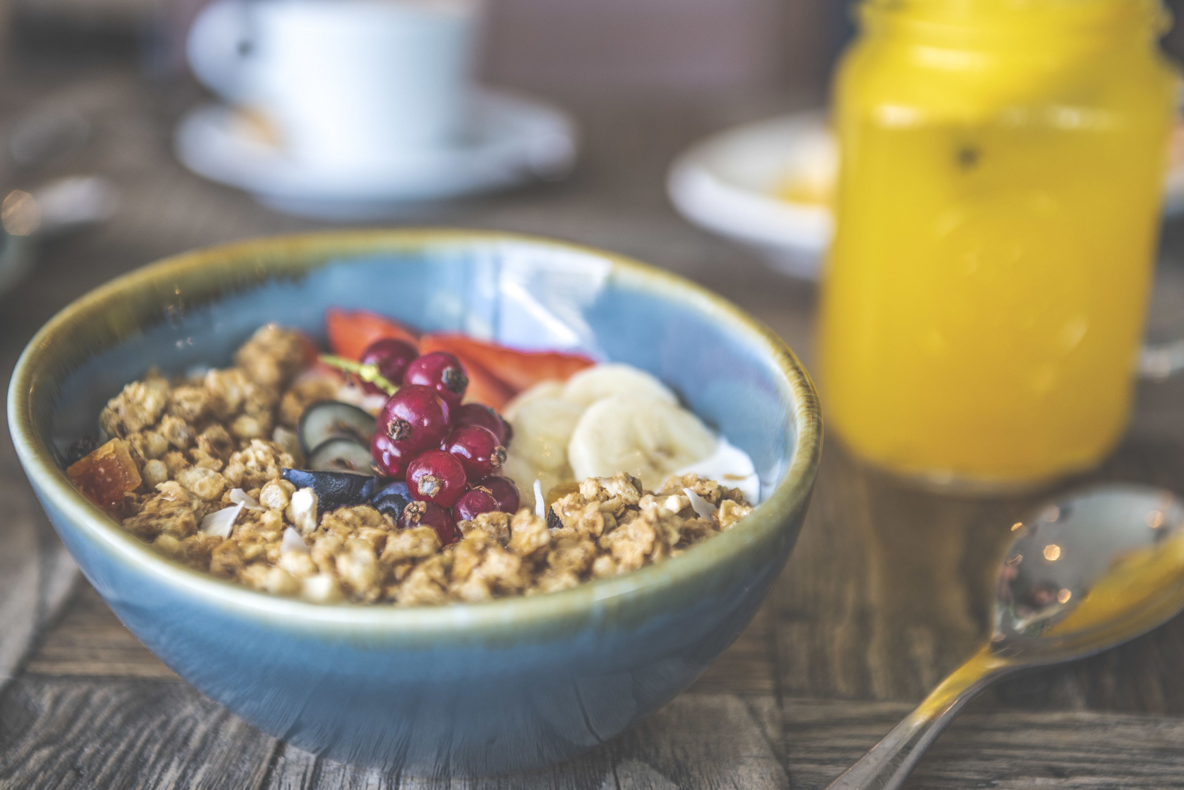 Un tazón de cereal con frutas y granola sobre una mesa de madera.