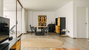 A modern living room with a wooden floor, a round woven rug, a dining table with chairs, a TV stand, and a bookshelf. - Sa Clau by Mambo (Sant Antoni de Portmany)
