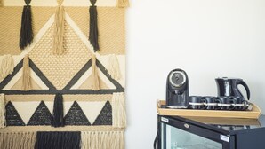 A wall with a geometric patterned tapestry and a coffee station with a coffee maker and cups. - Sa Clau by Mambo (Sant Antoni de Portmany)