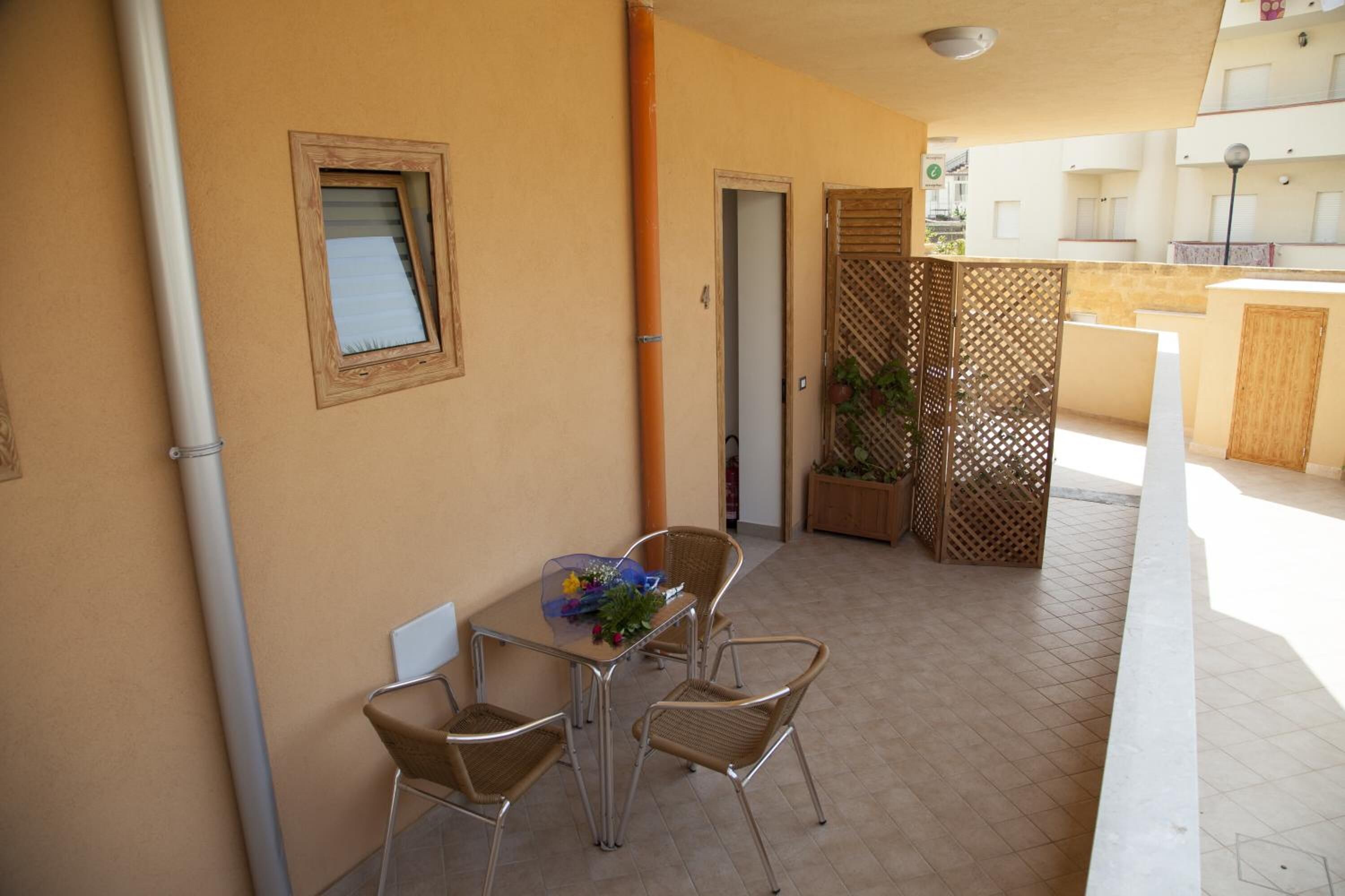 An outdoor patio with a table and chairs, a window, and a door.