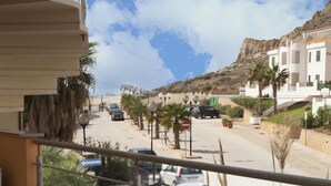 Un balcon aménagé pour le petit-déjeuner, avec vue sur une rue et des montagnes.