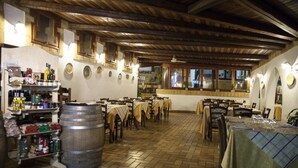 Un restaurant avec des poutres en bois, un sol carrelé et des tables recouvertes de nappes jaunes.