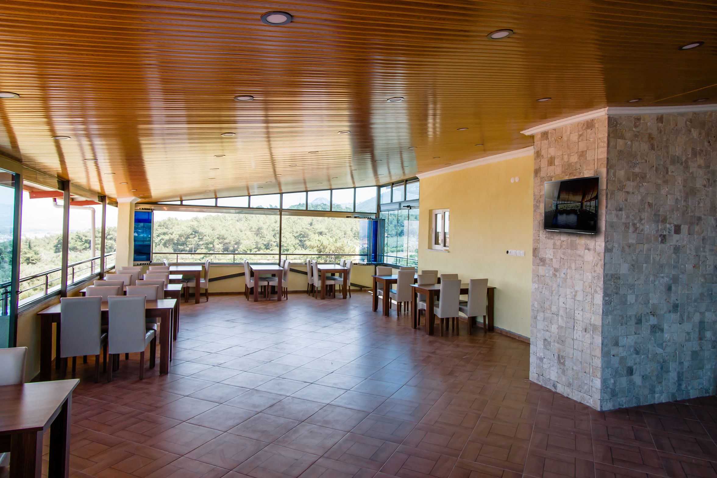 A spacious dining area with high ceilings and large windows offering a view of the outdoors.