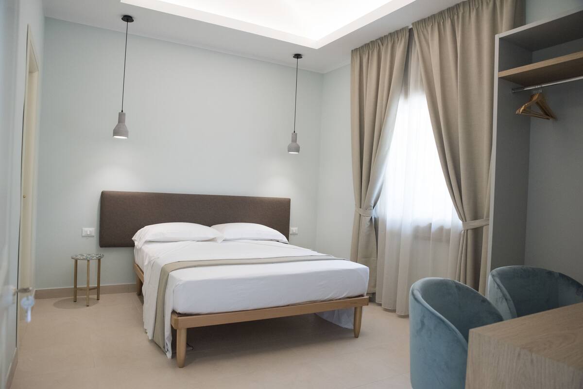 A bedroom with a bed, bedside tables, a wardrobe, and a chair.