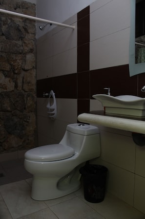 A bathroom with a toilet, a shower, and a sink.