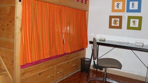 Una habitación con literas, un escritorio con silla y cuadros en la pared.