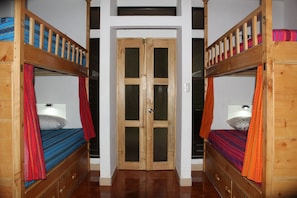 A room with two bunk beds, a wooden door, and a small window.