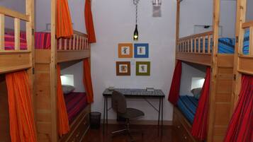 A dormitory room with bunk beds, a desk, and a chair.