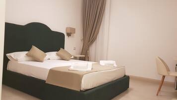 A neatly made bed with a dark headboard, a bedside table with a lamp, and a chair to the right.