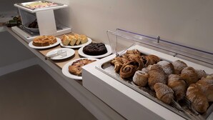 Un buffet proposant une variété de produits de boulangerie, notamment des gâteaux, des pâtisseries et du pain.