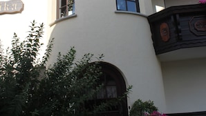 A building with a curved facade, multiple windows, and a balcony with wooden railings. - Pension Haus Erika (Stadtprozelten)
