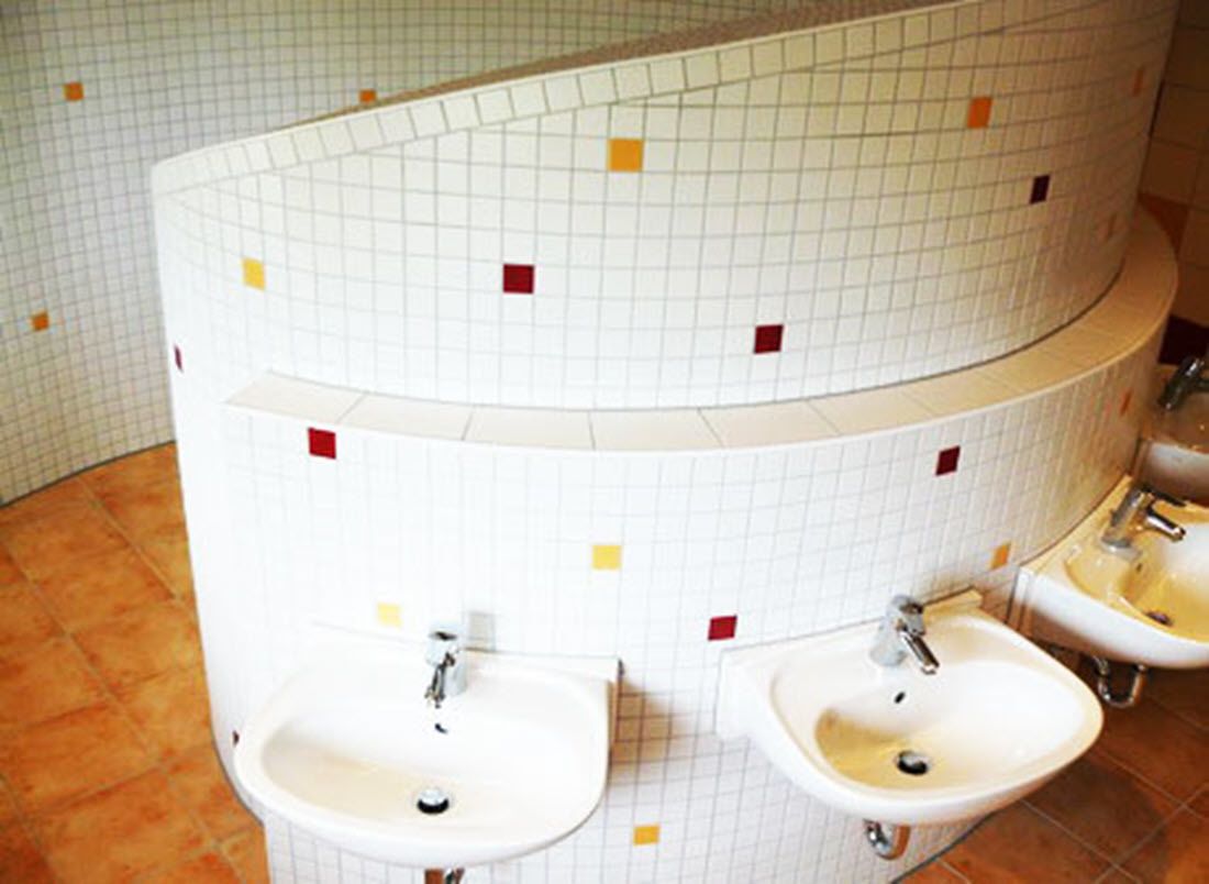 A bathroom with two sinks, tiled walls, and a curved design.