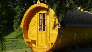 A wooden cylindrical building with a door and window, a small table, and a bench outside. - Camping Schwabenmühle (Weikersheim)