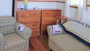 Ein Zimmer mit zwei karierten Sofas, einem Holzschrank und einem Fenster mit Vorhängen.