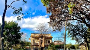 A park with a building in the background, surrounded by trees and grass. - B&B Santa Maria Apparente (Civitanova Marche)