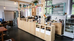 A wooden counter with a coffee machine, shelves with glassware, and a refrigerator. - Hostel La Maison Montreau (Montreuil)