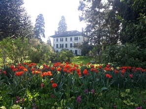 A large building with a symmetrical facade, surrounded by a well-maintained garden with a variety of flowers and trees. - Hostel La Maison Montreau (Montreuil)