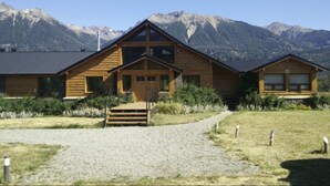 Un chalet en bois avec une entrée centrale, de grandes fenêtres et une allée gravillonnée.