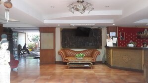 Una hall con reception, divano e un grande schermo a parete.