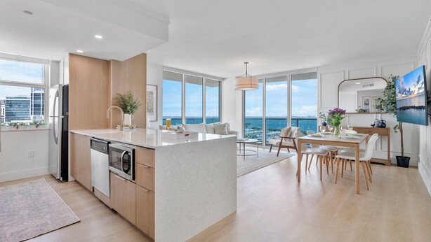 A modern kitchen with a central island, large windows, and a dining area with a view of the ocean. - Miami Vacation Rentals - Coconut Grove (Miami)