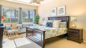 Une chambre à coucher avec un grand lit, une table de chevet, une commode, une chaise, un bureau et un ventilateur de plafond.